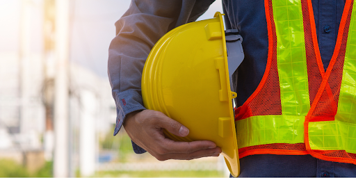 man holding hard hat and wearing safety vest outside facility